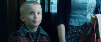 Movie still from “Filth” (2013), directed by Jon S. Baird – A young boy sitting in front of a woman; Close Up shot, Over the shoulder angle