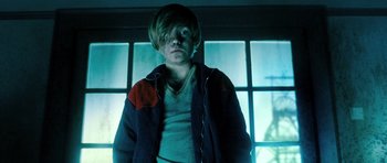 Movie still from “Filth” (2013), directed by Jon S. Baird – A man standing in front of a window in a room; Medium shot, Low angle