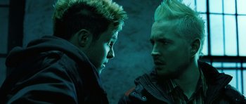 Movie still from “Filth” (2013), directed by Jon S. Baird – Two young men standing next to each other in a dark room; Close Up shot, Over the shoulder angle