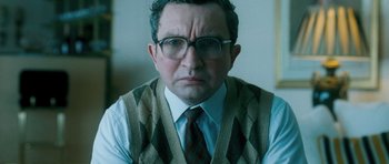 Movie still from “Filth” (2013), directed by Jon S. Baird – An older man wearing glasses and wearing a sweater vest; Close Up shot, Low angle