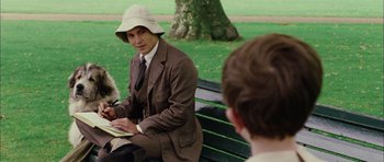 Movie still from “Finding Neverland” (2004), directed by Marc Forster – A man sitting on top of a wooden park bench; Medium shot, Over the shoulder angle