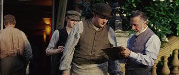 Movie still from “Finding Neverland” (2004), directed by Marc Forster – A man wearing a hat and vest looking down at a piece of paper; Medium shot, Low angle