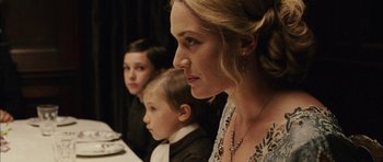 Movie still from “Finding Neverland” (2004), directed by Marc Forster – A woman and two children sitting in front of a table; Close Up shot, Over the shoulder angle