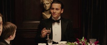 Movie still from “Finding Neverland” (2004), directed by Marc Forster – A man sitting at a dinner table holding a glass of wine; Close Up shot, Low angle