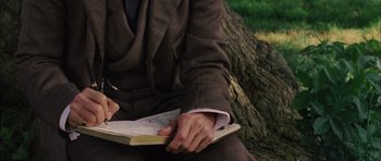 Movie still from “Finding Neverland” (2004), directed by Marc Forster – A man in a suit and tie holding a notebook; Close Up shot, High angle