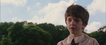 Movie still from “Finding Neverland” (2004), directed by Marc Forster – A young boy in a shirt and tie in front of trees; Close Up shot, Low angle