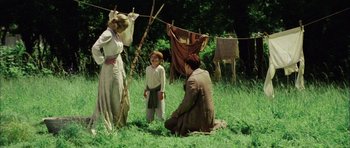Movie still from “Finding Neverland” (2004), directed by Marc Forster – Two people and a child in a field with clotheslines; Wide shot, Over the shoulder angle
