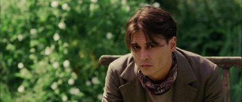 Movie still from “Finding Neverland” (2004), directed by Marc Forster – A man with long brown hair sitting in a park; Close Up shot, Over the shoulder angle