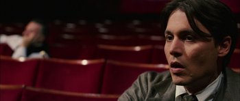 Movie still from “Finding Neverland” (2004), directed by Marc Forster – A man sitting in front of a row of red seats; Close Up shot, High angle