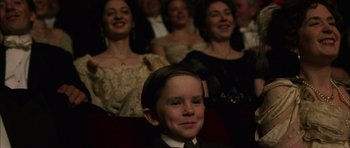 Movie still from “Finding Neverland” (2004), directed by Marc Forster – A boy in a suit and tie in front of a group of people; Close Up shot, High angle