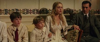 Movie still from “Finding Neverland” (2004), directed by Marc Forster – A woman sitting next to a young boy in front of a fireplace; Medium shot, High angle