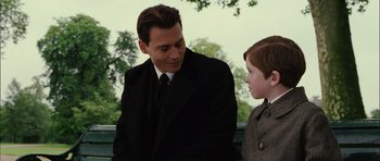 Movie still from “Finding Neverland” (2004), directed by Marc Forster – A man in a suit and tie talking to a young boy; Medium shot, Over the shoulder angle