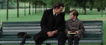 Movie still from “Finding Neverland” (2004), directed by Marc Forster – A man sitting on top of a wooden bench next to a boy; Medium shot, Over the shoulder angle