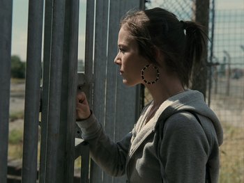 Movie still from “Fish Tank” (2009), directed by Andrea Arnold – A young woman holding on to a metal gate; Close Up shot, Over the shoulder angle