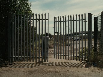 Movie still from “Fish Tank” (2009), directed by Andrea Arnold – A person standing in front of a gate; Extreme Wide shot, Over the shoulder angle