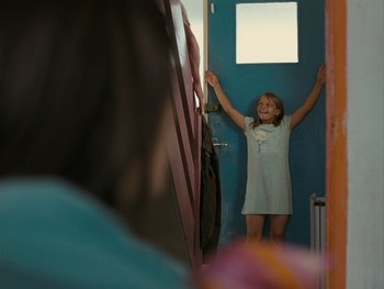 Movie still from “Fish Tank” (2009), directed by Andrea Arnold – A little girl standing in front of a blue door; Medium shot, Over the shoulder angle