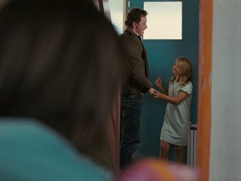 Movie still from “Fish Tank” (2009), directed by Andrea Arnold – A man and a woman holding hands in front of a blue door; Medium shot, Over the shoulder angle