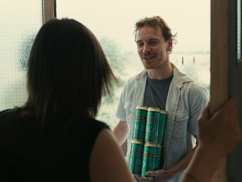 Movie still from “Fish Tank” (2009), directed by Andrea Arnold – A man holding a can of beer in front of a woman; Medium shot, Over the shoulder angle