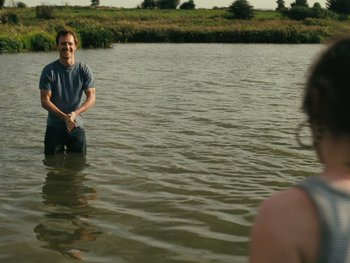 Movie still from “Fish Tank” (2009), directed by Andrea Arnold – A man standing in the water holding a frisbee; Wide shot, Over the shoulder angle