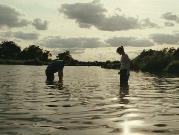 Movie still from “Fish Tank” (2009), directed by Andrea Arnold – Two people in a body of water with trees in the background; Extreme Wide shot, Low angle