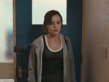 Movie still from “Fish Tank” (2009), directed by Andrea Arnold – A woman standing in front of an open door; Medium shot, Over the shoulder angle