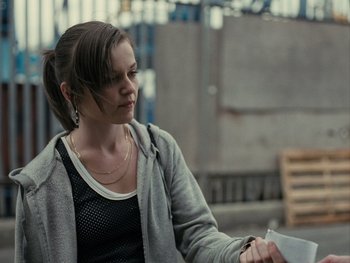 Movie still from “Fish Tank” (2009), directed by Andrea Arnold – A woman is looking down at a piece of paper; Medium shot, Over the shoulder angle