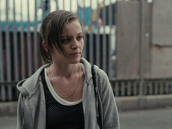 Movie still from “Fish Tank” (2009), directed by Andrea Arnold – A young woman is walking down the sidewalk; Close Up shot, Over the shoulder angle