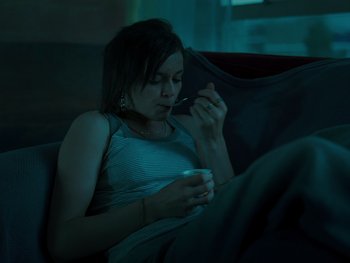 Movie still from “Fish Tank” (2009), directed by Andrea Arnold – A woman sitting on a couch holding a cup of coffee; Medium shot, High angle