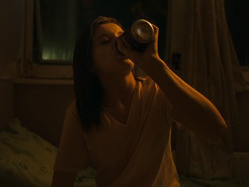 Movie still from “Fish Tank” (2009), directed by Andrea Arnold – A woman is drinking a can of beer; Medium shot, High angle
