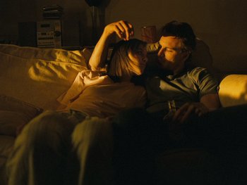 Movie still from “Fish Tank” (2009), directed by Andrea Arnold – A man and a woman kissing on a couch; Medium shot, Over the shoulder angle