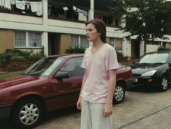Movie still from “Fish Tank” (2009), directed by Andrea Arnold – A person standing in front of a car; Medium shot, Low angle