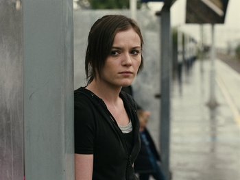 Movie still from “Fish Tank” (2009), directed by Andrea Arnold – A young woman standing next to a wall on the sidewalk; Close Up shot, Over the shoulder angle
