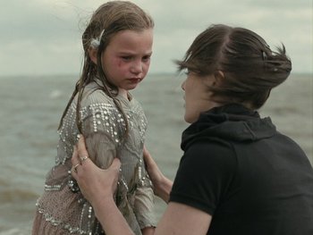 Movie still from “Fish Tank” (2009), directed by Andrea Arnold – A young girl being held down by a woman on the beach; Medium shot, Over the shoulder angle