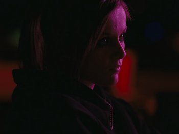 Movie still from “Fish Tank” (2009), directed by Andrea Arnold – A woman in a black jacket is in the dark; Close Up shot, Over the shoulder angle