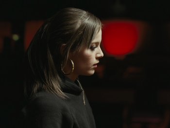 Movie still from “Fish Tank” (2009), directed by Andrea Arnold – A woman with long brown hair wearing large hoop earrings; Close Up shot, Over the shoulder angle