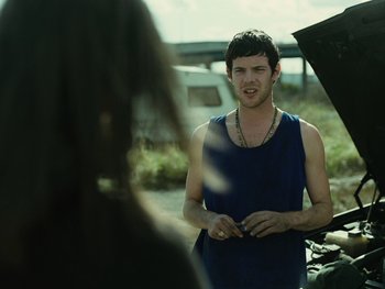 Movie still from “Fish Tank” (2009), directed by Andrea Arnold – A man standing in front of a woman in front of an airplane; Medium shot, Over the shoulder angle