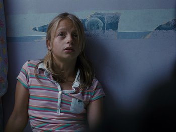 Movie still from “Fish Tank” (2009), directed by Andrea Arnold – A young girl sitting against a wall looking sad; Close Up shot, High angle