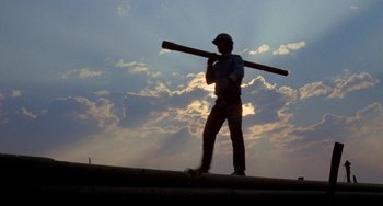 Movie still from “Five Easy Pieces” (1970), directed by Bob Rafelson – A man holding a baseball bat while standing on top of a hill; Medium shot, Low angle