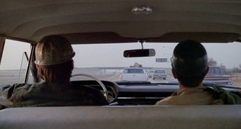 Movie still from “Five Easy Pieces” (1970), directed by Bob Rafelson – Two men are driving in the back of a car; Wide shot, Over the shoulder angle