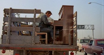 Movie still from “Five Easy Pieces” (1970), directed by Bob Rafelson – A man sitting on the back of a moving truck; Wide shot, Low angle