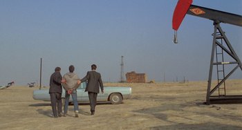 Movie still from “Five Easy Pieces” (1970), directed by Bob Rafelson – A group of people standing next to an old car; Wide shot, High angle