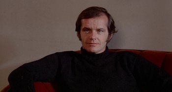 Movie still from “Five Easy Pieces” (1970), directed by Bob Rafelson – A man sitting on a red chair wearing a black sweater; Close Up shot, Low angle