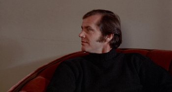 Movie still from “Five Easy Pieces” (1970), directed by Bob Rafelson – A man sitting on a couch looking to his left; Close Up shot, Low angle