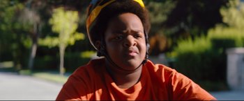 Movie still from “Good Boys” (2019), directed by Gene Stupnitsky – A young boy wearing an orange t - shirt and a yellow helmet; Close Up shot, Over the shoulder angle