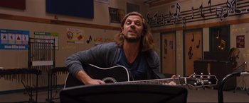 Movie still from “Good Boys” (2019), directed by Gene Stupnitsky – A man with long hair is playing a guitar; Medium shot, Over the shoulder angle