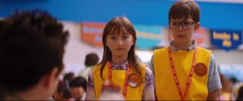 Movie still from “Good Boys” (2019), directed by Gene Stupnitsky – A young girl in a yellow vest is standing in front of other young people; Close Up shot, Over the shoulder angle