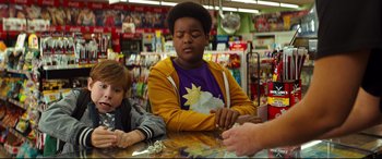 Movie still from “Good Boys” (2019), directed by Gene Stupnitsky – A boy sitting at a table in a toy store with another boy; Medium shot, Over the shoulder angle