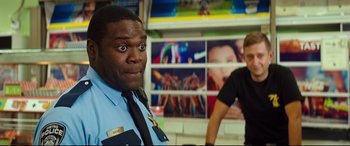 Movie still from “Good Boys” (2019), directed by Gene Stupnitsky – A man in a police officer's uniform looks at the camera while a man in a black shirt looks at the camera; Medium shot, Over the shoulder angle