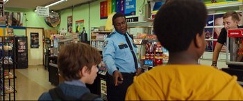 Movie still from “Good Boys” (2019), directed by Gene Stupnitsky – A man in a police uniform standing in a store; Medium shot, Over the shoulder angle
