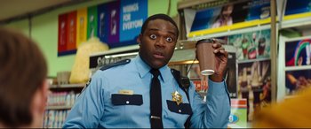 Movie still from “Good Boys” (2019), directed by Gene Stupnitsky – A police officer holding a cup of coffee in his hand; Medium shot, Over the shoulder angle